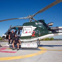 Paco Lucas (izda.) y Juan Cruz Nicolás junto al helicóptero de extinción de incendios que pilotan.