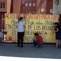 Convocantes de la concentración de mañana martes, en el Instituto Profesor Máximo Trueba de Boadilla del Monte, contra los recortes educativos, colocan en el centro el cartel de la misma.